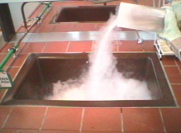 Fluessiger Stickstoff wird in Waschbecken mit heissem Wasser gegossen.